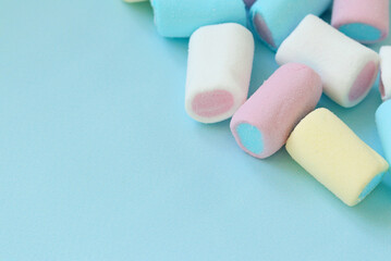 Colorful pastel marshmallows on a blue background. Selective focus. Space for text. Keyboard layout. Copy space