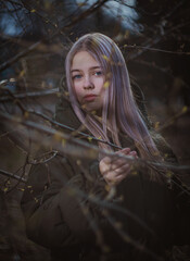 A girl in the Park in early spring observes the branches of trees