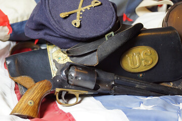 Civil War collectible antique pistol, hat and gear of the Union army on an American flag.