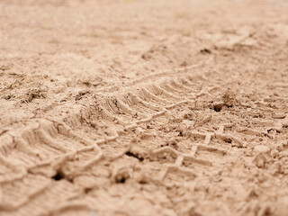 Tire tracks in beige fine dry sand with a focus on the middle level.