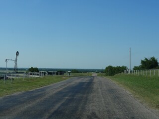Asphalt road going up and down the hills by farmlands in Oklahoma
