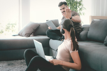 Cheerful couple make hi five during work on laptop computer at home, searching online information...