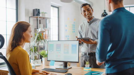 Fototapeta premium Three Mobile Software Developers Work on Desktop Computer, They Discuss Smartphone Application Design Use Touch Screen Digital Tablet. Modern Stylish Office with Diverse Team of Professionals Working.