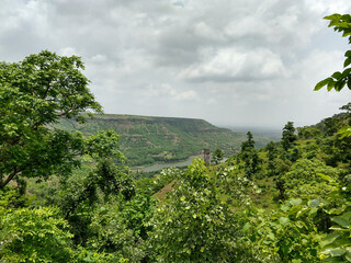 Landscape view of a valley, An edge of the hill and a little lake at the bottom of that hill can be seen through the trees
