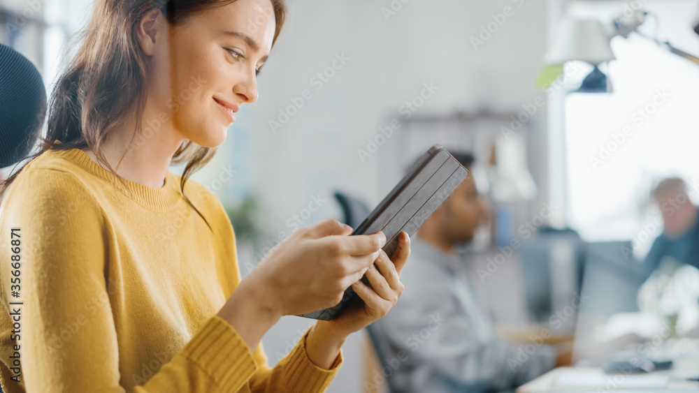 Aufkleber talented female designer sitting at her desk she's holding and using touch screen digital tablet com