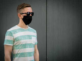 A man wearing a black protective mask.Looking to the right. On a Gray background. During the coronavirus pandemic