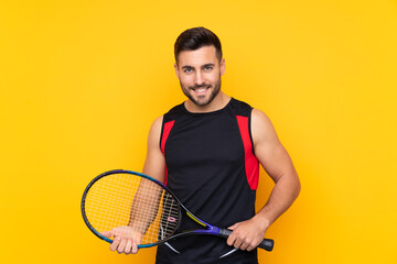 Man over isolated yellow background playing tennis