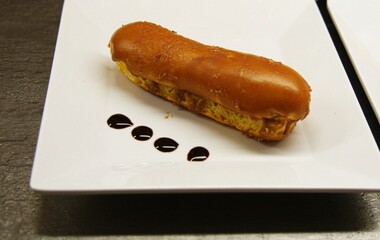 Close up of a delicious mocha éclair adorned with four drops of chocolate syrup
