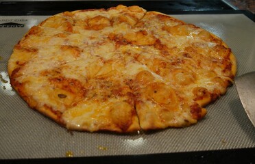 Thin crust cheesy pizza heating up on the grill