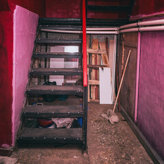 Fototapeta na wymiar A metal staircase leading to a basement with red walls
