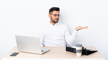 Young businessman in a workplace holding copyspace with doubts
