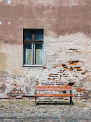 Fototapeta na wymiar A new wooden bench on the background of an old brick wall of a house, Toruń, Poland