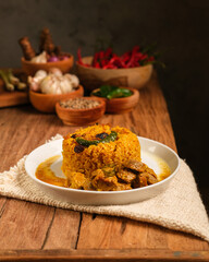 Indian Mutton Biryani Dish served on wooden table. Typical food from India, made from goat meat mixed with spices and basmati rice