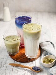 Three glasses of matcha coffee in green and blue on a white background