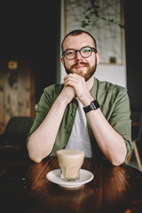 Handsome young man in eyeglasses resting in cafe