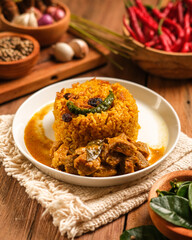 Indian Mutton Biryani Dish served on wooden table. Typical food from India, made from goat meat mixed with spices and basmati rice