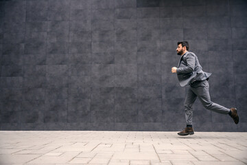 Young attractive bearded businessman running to work.