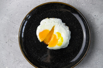 Fried egg toast on black plate on gray concrete background. Tasty healthy breakfast. Morning food, top veiw