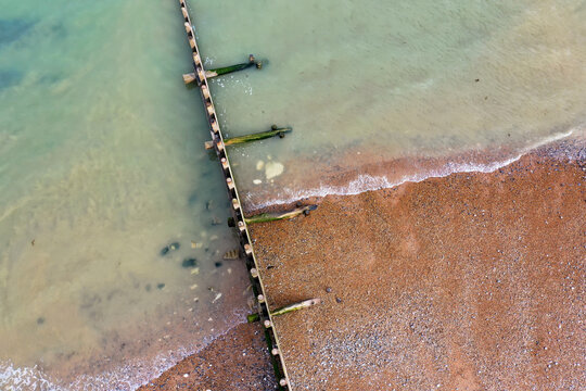 beach aerial view with groin and waves lapping the shoreline, taken in Eastbourne, East Sussex