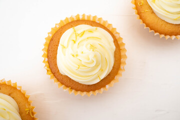 Three frosted cupcakes arranged on diagonal line through centre of the image.  Plain background with copy text space and shot in flat lay top down view.