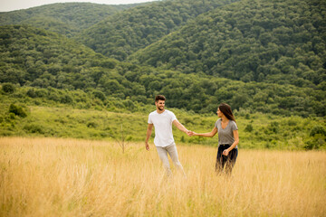 Happy young couple in love walking through grass field