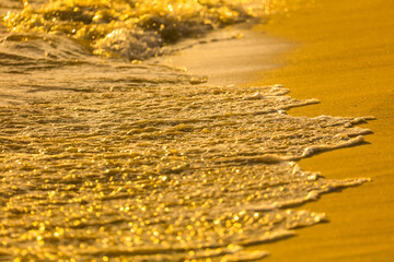 Water on the sandy shore at sunset.