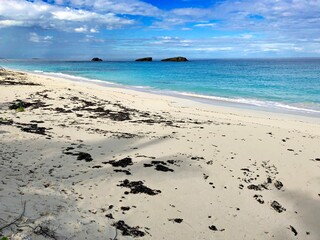 Soft white sand at the Three Sisters beach in Georgetown, Bahamas on a beautiful day with gorgeous clouds