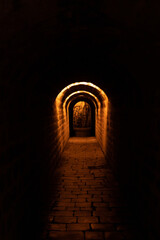 more than a century old dark paved and historic tunnel in Prague with orange light