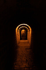 Fototapeta premium more than a century old dark paved and historic tunnel in Prague with orange light