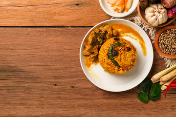 Indian Mutton Biryani Dish served on wooden table. Typical food from India, made from goat meat mixed with spices and basmati rice