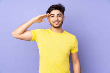 Arabian handsome man over isolated background saluting with hand with happy expression