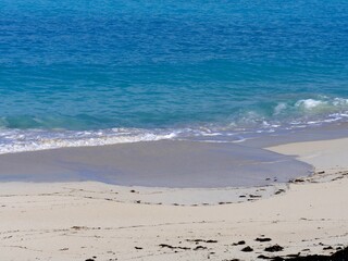 Small gentle waves create patterns in the pristine white sands of a tropical beach