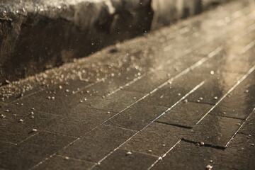 contrasty filled frame background wallpaper photo of dark wet shiny tile with drops of rain and water, reflecting the rays of light of the yellow sun