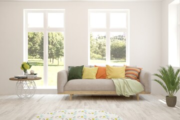 Fototapeta premium White living room with sofa and summer landscape in window. Scandinavian interior design. 3D illustration