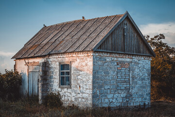 An old abandoned house stands alone among the greenery in the summer