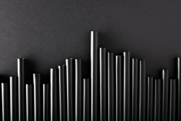 Black plastic cocktail straws arranged as fluctuating graph chart