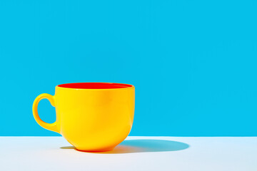 Yellow coffe mug on the table against blue background