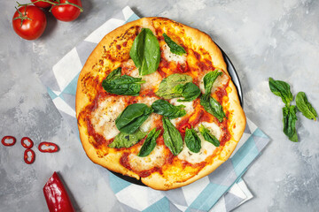 Homemade pizza margarita with mozzarella, tomatoes and basil on the concrete background