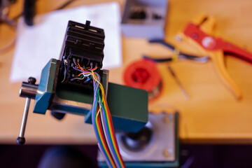 Closeup image of soldering station with colored electrical cables and wires in a vice machine