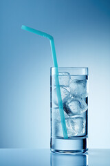 Glass of cold water with ice and straw on table