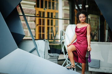 Portrait of a beautiful natural young African woman with afro hair. Black model in red silk dress.