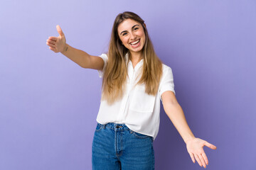 Young woman over isolated purple background presenting and inviting to come with hand