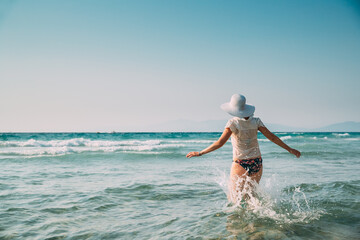 Young Caucasian Lady Woman In Swimsuit And Summer Hat Running In Sea. Vacation On Sea Ocean Beach