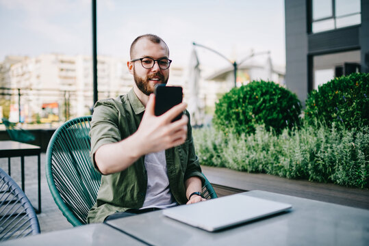 Thoughtful hipster guy updating profile on telephone device using high speed internet connection