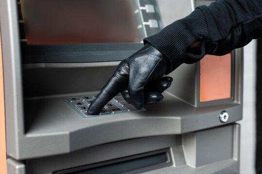 Cropped view of burglar in leather glove using atm
