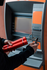 Cropped view of burglar holding dynamite sticks and lighter near atm