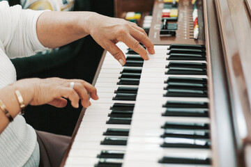 Fototapeta premium Close up elderly grandmother hand playing piano in living room at home, old woman activity lifestyle after retirement , living quality and insurance concept