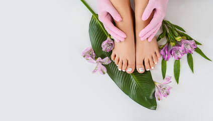 Beautiful perfect female skin legs feet top view with tropical flowers and green palm leaf. Nail...