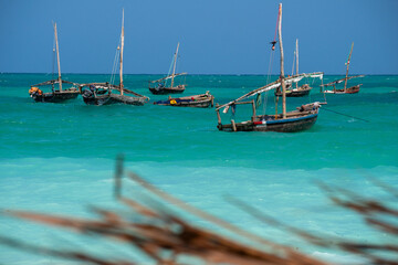 Obraz premium Anchored Traditional wooden dhow boats on the amazing turquoise water in the Indian ocean at Nungwi village, Zanzibar, Tanzania