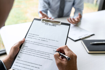 Senior committee manager reading a resume during a job interview, Employer interviewing to ask young male job seeker for recruitment talking in office